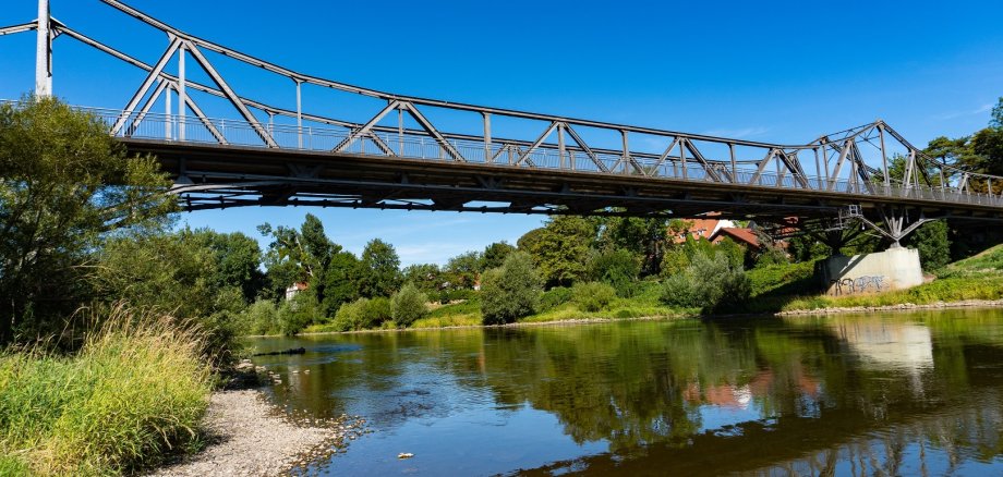 Eine alte Eisenbrücke führt über einen Fluss